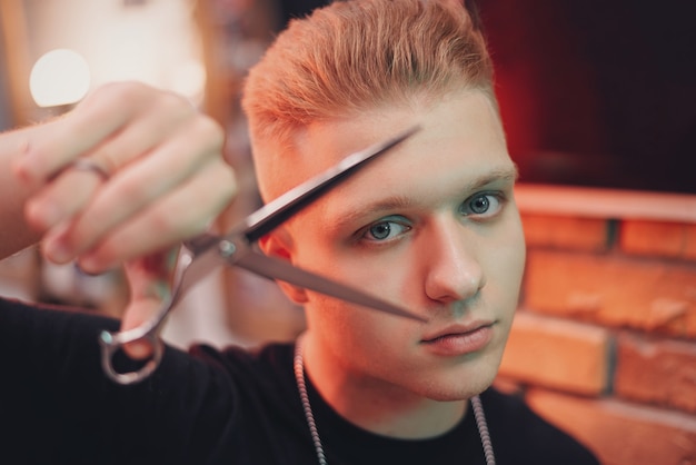 Master barber holds scissors near the face