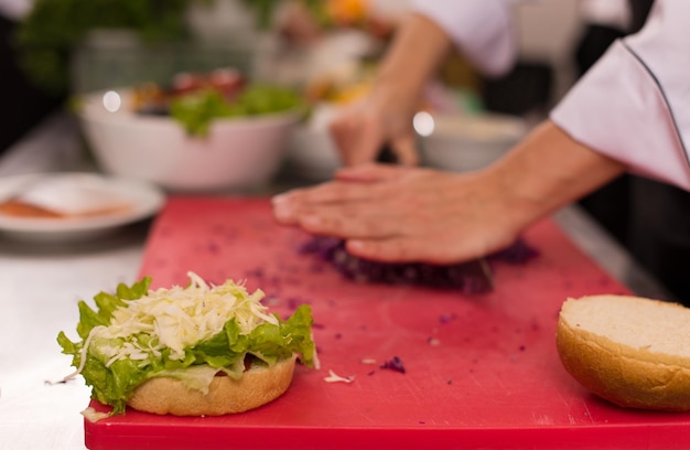 master chef cutting salad for a burger in the rastaurant kitchen