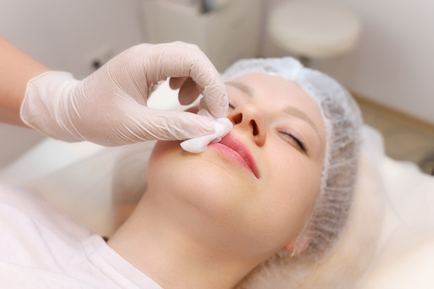 A master cosmetologist wipes blood droplets from his lips after a shot of hyaluronic acid