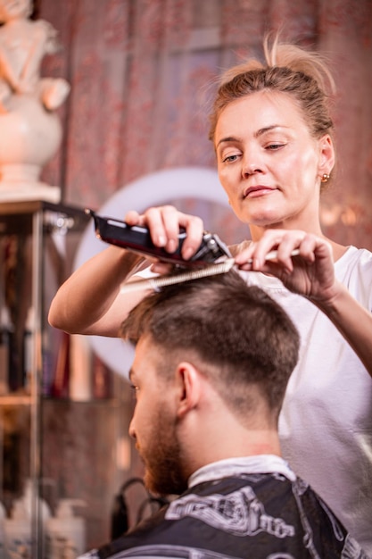 The master cuts the hair and beard of a man in a barbershop a hairdresser does a haircut for a young man Beauty concept self care