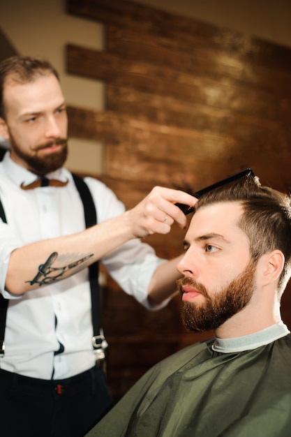 Master cuts hair and beard of men in the barbershop