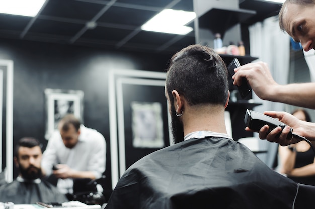 Master cuts hair and beard of men in the barbershop