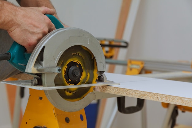 Master cutting hand electric saw cut a piece of wood laminated shelves in apartment