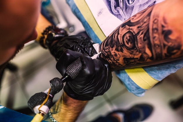 Master drawing tattoo on arm