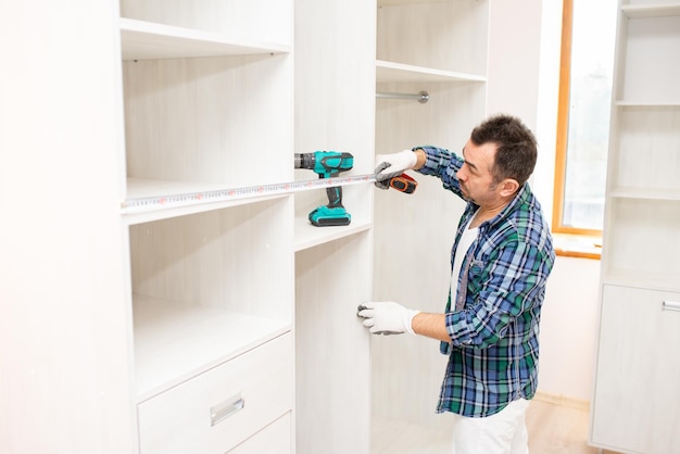 Master furniture maker measures the width of the cabinet with a tape measure