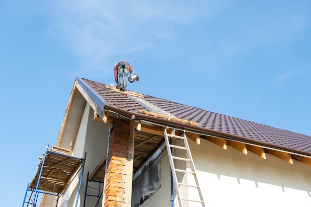 The master for the installation of ventilation pipes and the installation of the chimney of the furnace works on the roof of the house