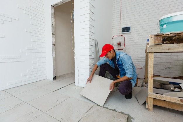 master is installing floor ceramic tile in a room, pressing down and leveling, interior finishing of premises of a living houses