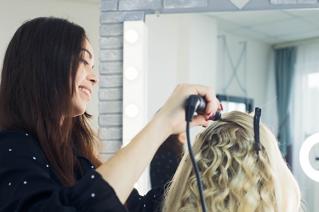 The master makes a hairstyle for a girl, beautiful curls