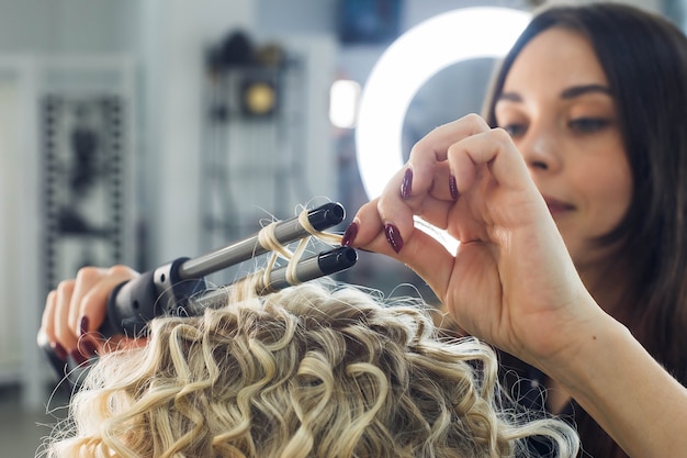 The master makes a hairstyle for a girl, beautiful curls