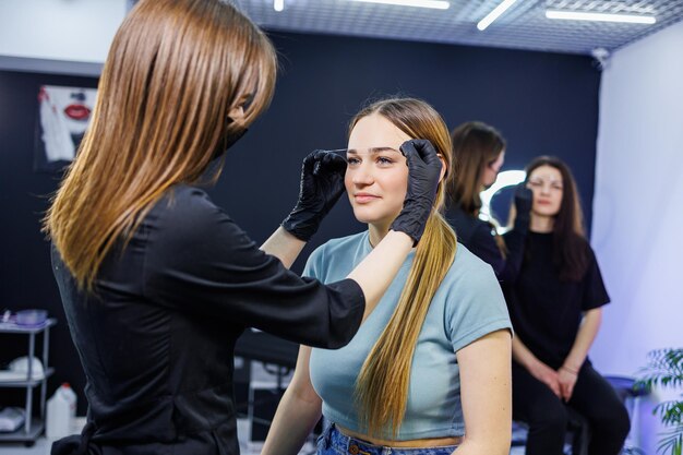 The master marks the woman's face before permanent eyebrow makeup Eyebrow tattoo Beauty procedure for a woman's face