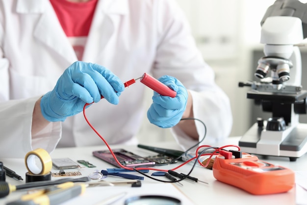 Master repairman checking battery charge using tester closeup