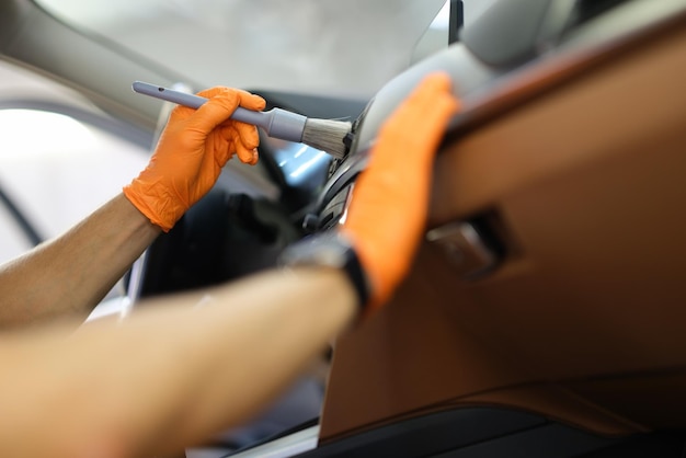 Master repairman cleans the car air conditioner with brush in workshop closeup