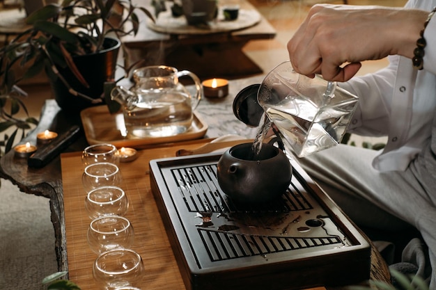 Master serving traditional chinese tea ceremony and pouring oolong from teapot with vapor on a dark background