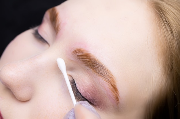 the master smoothes and removes excess eyebrow makeup with a cotton swab