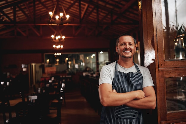 The master taking a break Portrait of a confident middle aged business owner standing with arms folded under a doorway at a beer brewery during the day