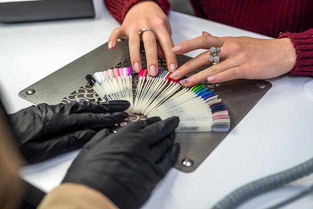 Photo master with a customer choosing color of nail polish in beauty salon