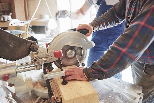 Master in a work suit using a grinder on a sawmill.