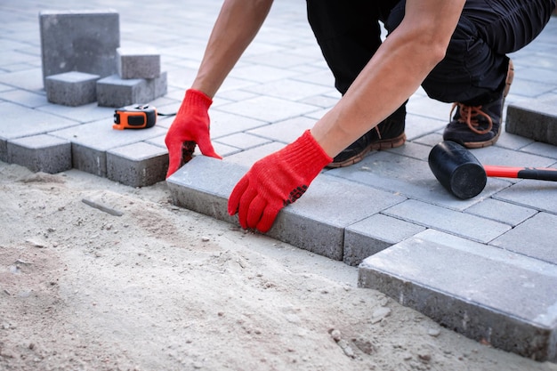 The master in yellow gloves lays paving stones