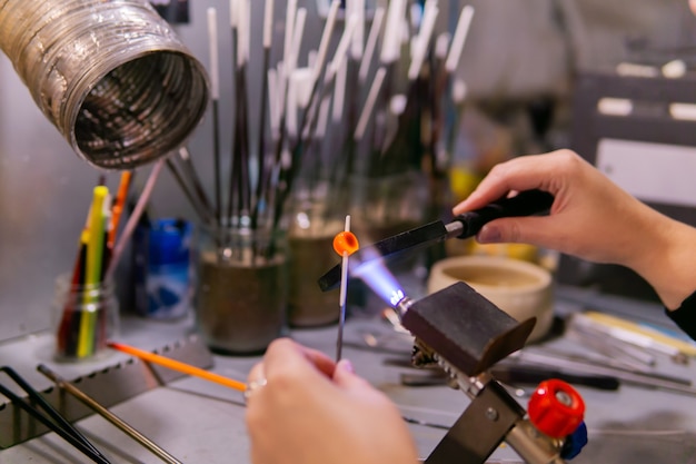 Masters hands forming a glass bead during beadmaking in a glassblowing workshop