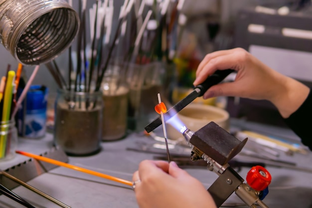 Masters hands forming a glass bead during beadmaking in a glassblowing workshop