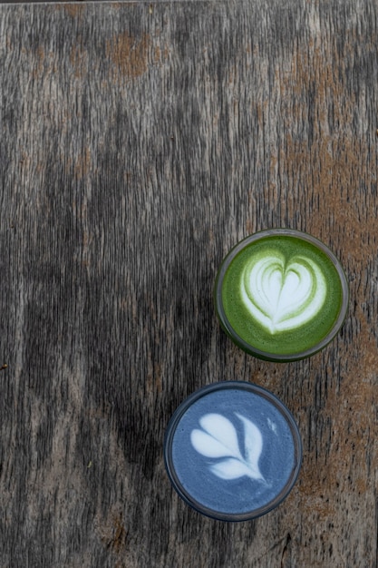 Matcha green and blue tea latte in cups. Healthy drink. Traditional japanese drink on black wooden background. Place for text.