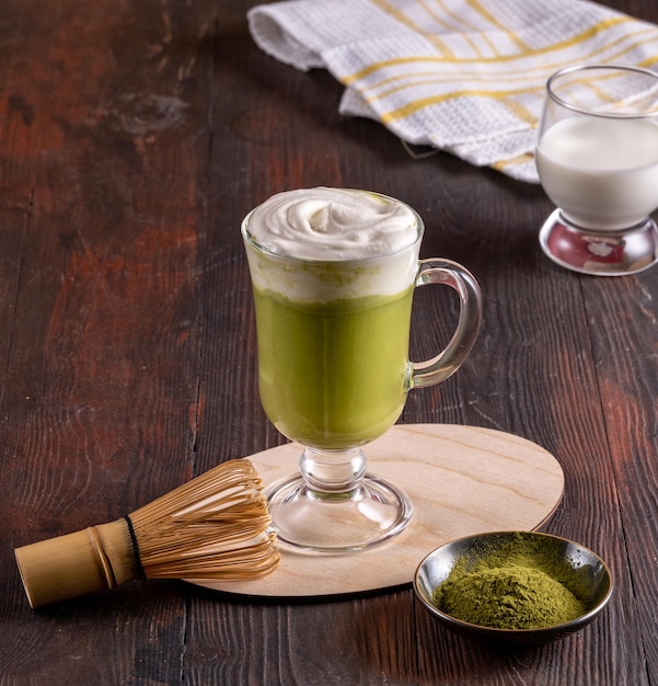 Matcha green latte tea matcha powder and bamboo whisk on wood background