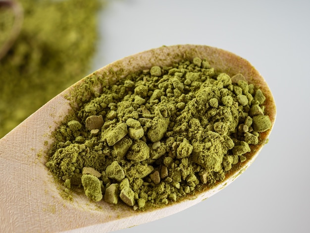 Matcha tea powder of green color is scattered on a white background. Copy space.