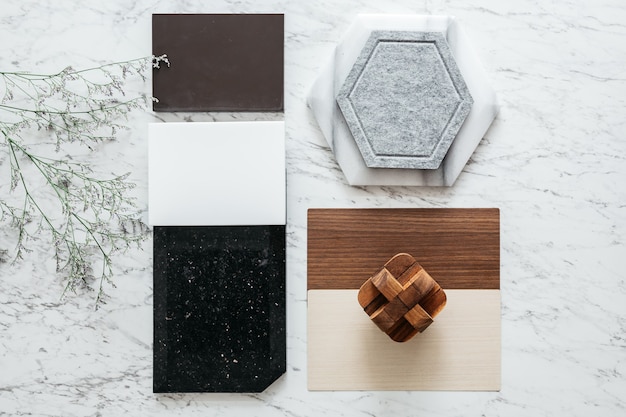 Photo material selections including granite tile, marble tile, acoustic tile, walnut and ash wood laminate with plant on marble top table.