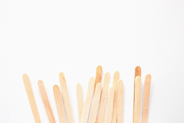 Materials for depilation of eyebrows and delicate areas Wooden sticks lie on a white background