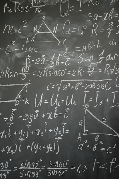 Math formulas written in white chalk on black board vertical shot