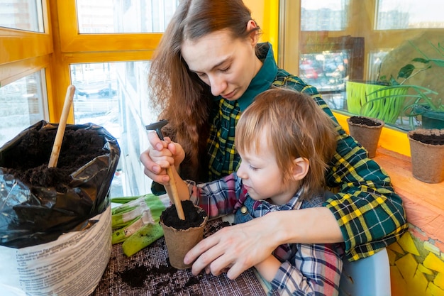 Mather and son prepare a hole and plant seeds in a peat pot