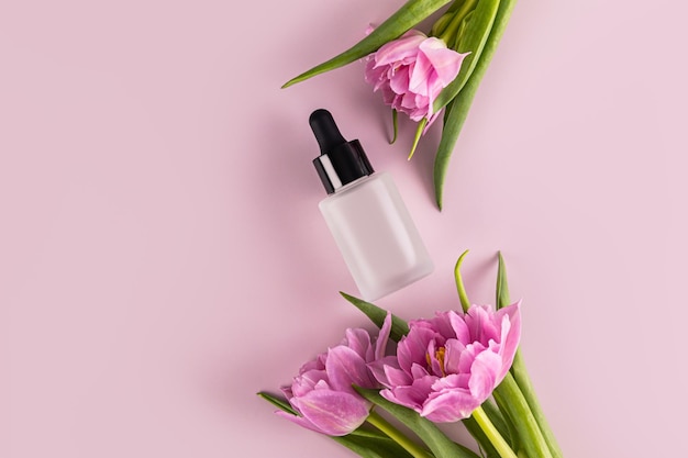 Matte Cosmetic Dropper Bottle with Natural Organic Product Face and Neck Serum lilac background Flowers A copy space