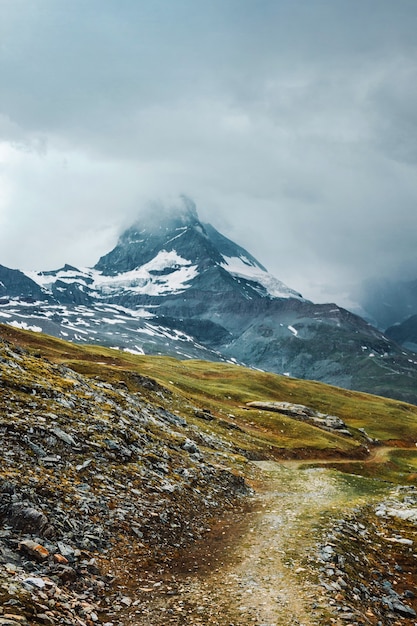 Matterhorn in clouds ountain path grass stones Zermatt Swiss Alps Adventure in Switzerland