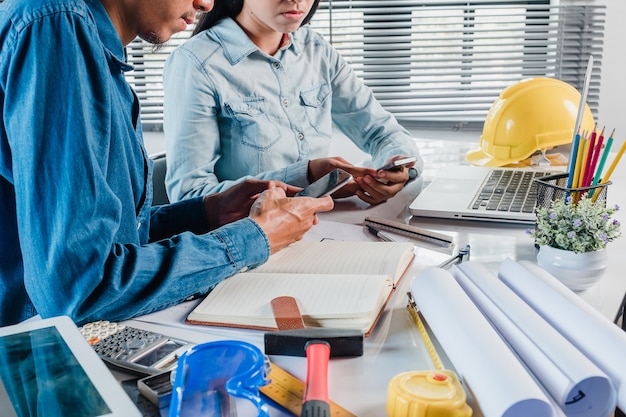 Mature architect engineer man using a smartphone to discuss information with a younger colleague.