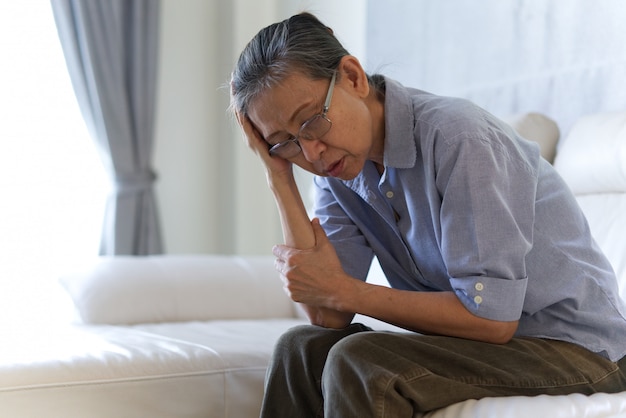 Mature Asian senior woman sitting and having a headache.