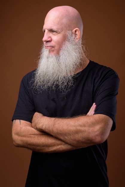 Mature bald man with long gray beard on brown