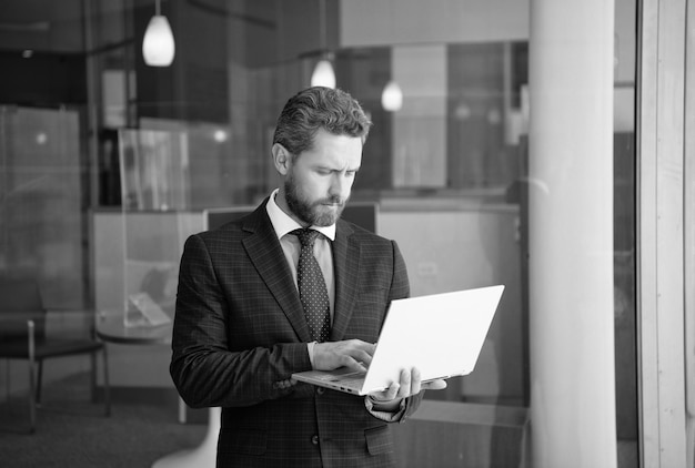 Mature bearded ceo man in suit work online on wireless computer outside the office freelancer