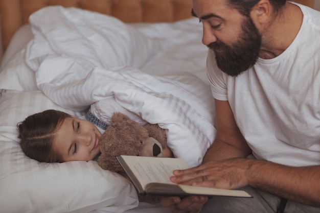 Mature bearded man resting at home with his little daughter