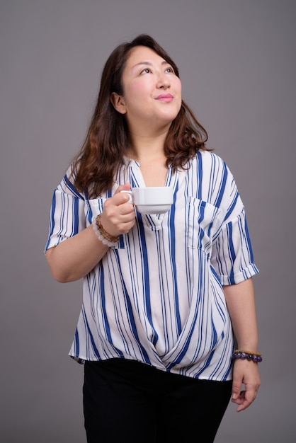 mature beautiful Asian businesswoman holding cup of coffee