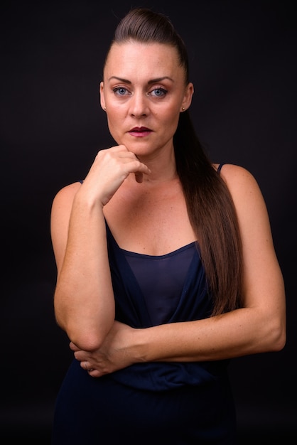  mature beautiful woman with brown hair against black wall