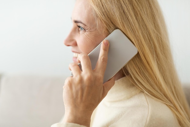 Photo mature blond woman talking on phone side view