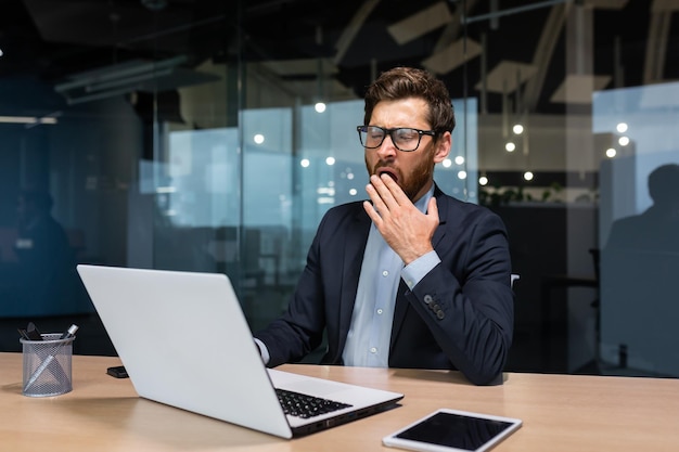 Mature bored businessman working inside modern office building boss in glasses and business suit