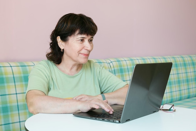 Mature brunette woman works in front of a laptop in a cafe