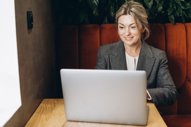 Mature business woman restaurant administrator sitting and working on laptop