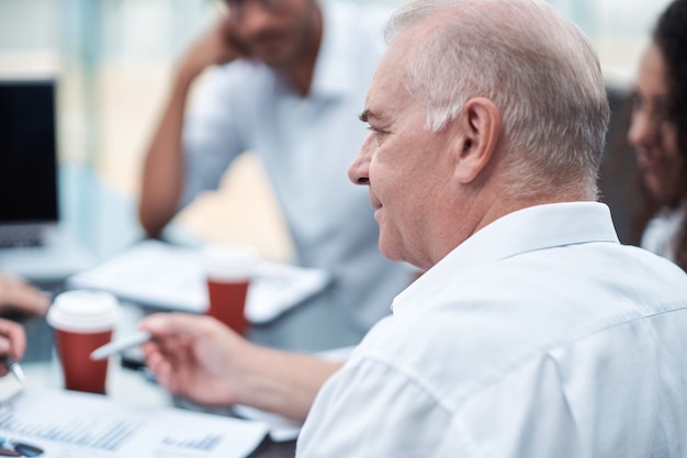 Mature businessman discussing financial documents with a working group  closeup