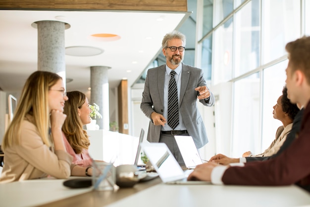 Mature businessman explaining strategy to group of multiethnic business people while working on new project in the office