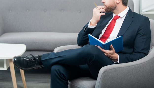 Mature businessman in suit sit in office making notes in notebook make decision