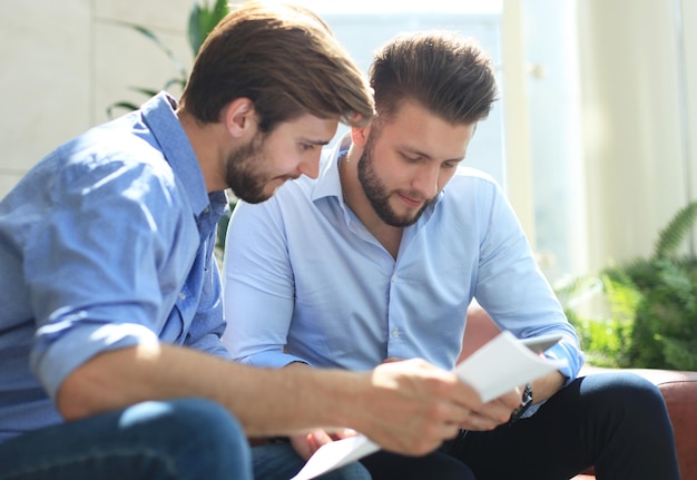 Mature businessman using a digital tablet to discuss information with a younger colleague in a modern business office