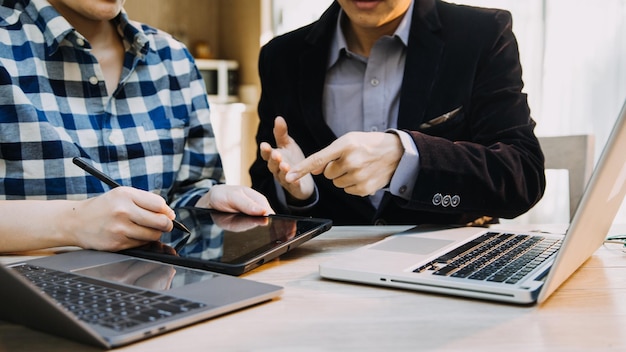 Mature businessman using a digital tablet to discuss information with a younger colleague in