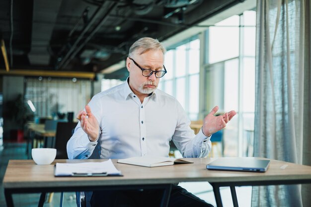 Photo mature businessman working while sitting in the office a middleaged executive is working in the office using a laptop emotional businessman